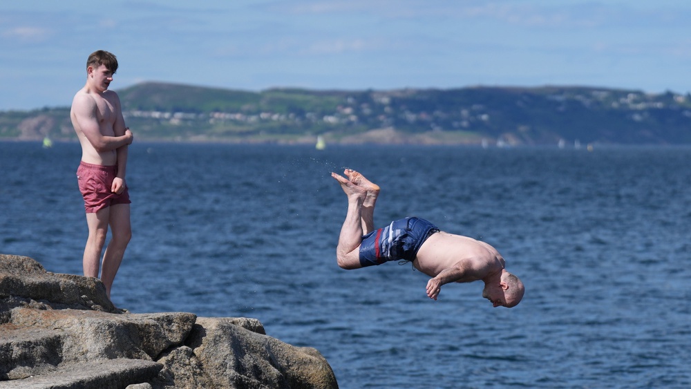 People jump into the water at the Forty Foot bathing pool on the southern tip of Dublin Bay at Sandycove, Dublin (Niall Carson/PA) (PA Wire)