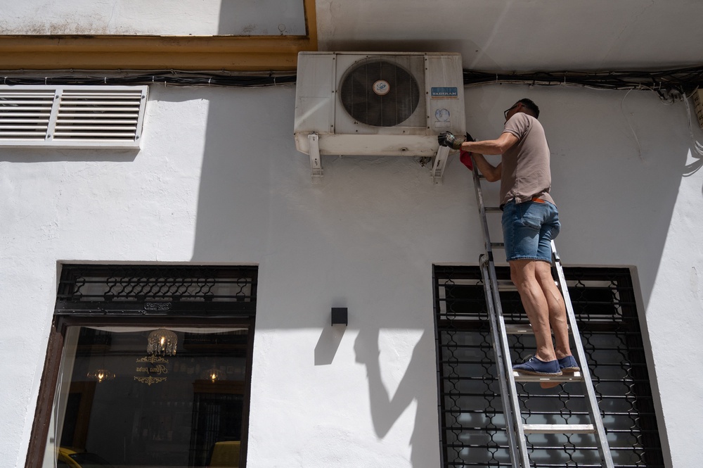 A technician repairs an air conditioner on the facade of a restaurant in the city centre of Ronda in southern Spain (AFP/Getty)
