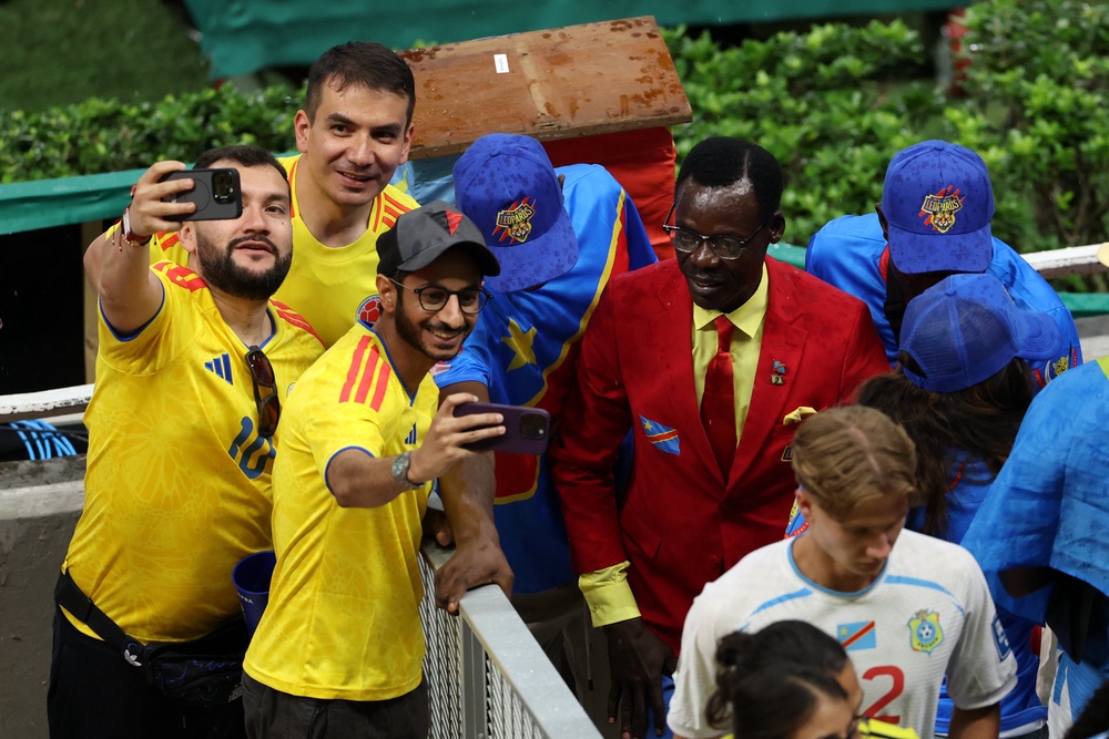 Colombia fans pose for photos with Congo DR fan Michel Nkuka Mboladinga (Getty)