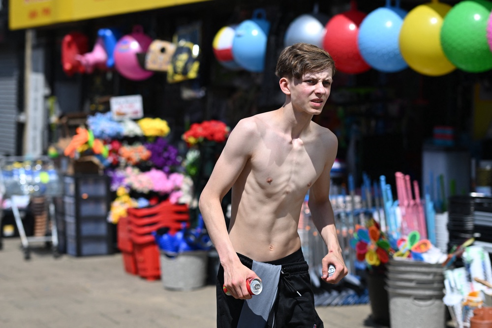 A pedestrian carries drinks in the sunshine in the town centre in Huddersfield in Northern England on 23 June 2026 (AFP/Getty)
