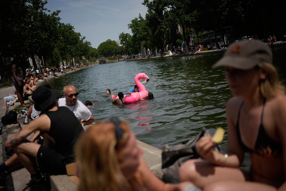Parisians bath in the Canal Saint-Martin in Paris, as the national weather service, Meteo France, placed 54 departments, about half the country, under a red heat wave alert, Tuesday, June 23, 2026 (AP)