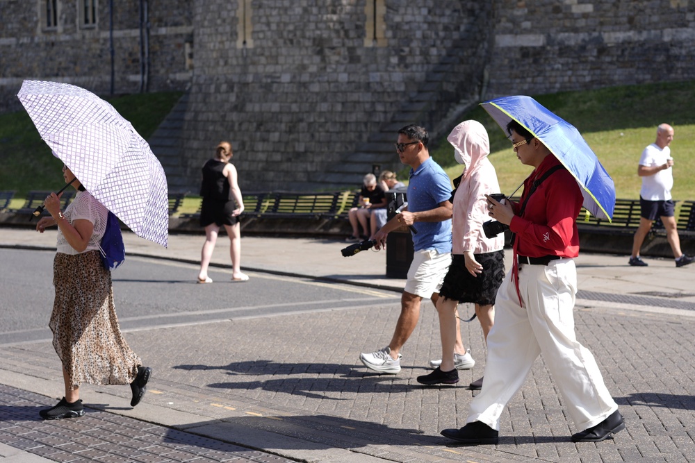 People use umbrellas to shade themselves from the sun in Windsor, Berkshire (PA)