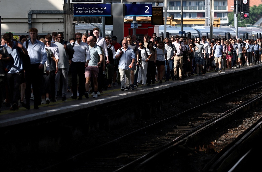 Commuters battle the heat at Waterloo Station in London (Reuters)
