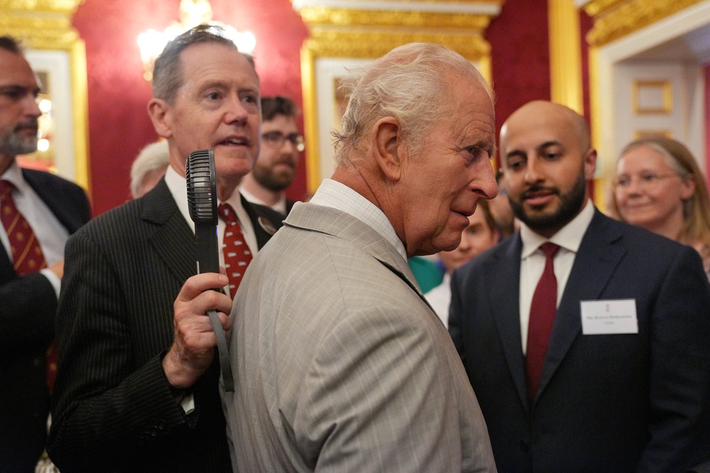 An aide held a fan close to Charles as he met guests at the event (Yui Mok/PA) (PA Wire)