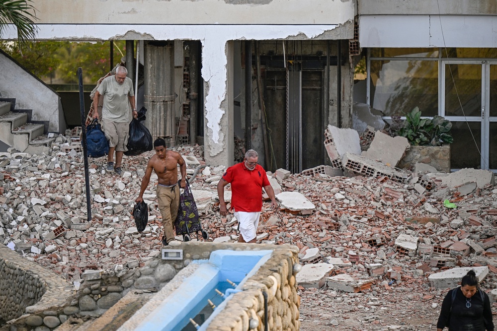 People carry their belongings out of a damaged building following an earthquake in Catia La Mar, La Guaira state, (AFP/Getty)
