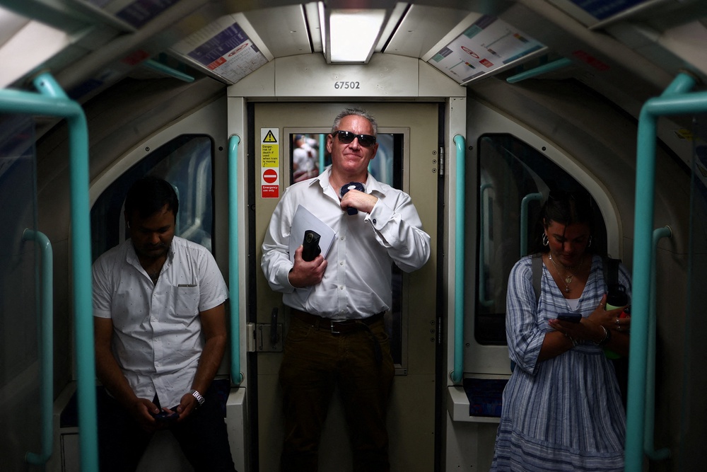A man uses a fan to cool down while travelling on the Waterloo and City line tube train as Britain experiences record temperatures disrupting schools and transport networks, in London, Britain, June 25, 2026 (Reuters)