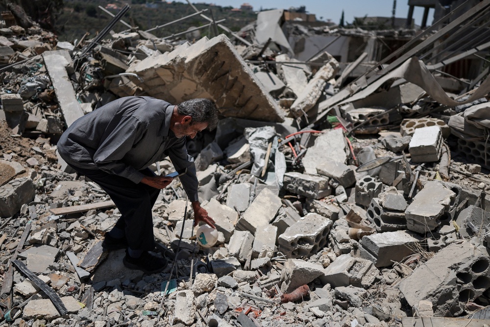 A 76-year-old displaced Lebanese man shows his house, destroyed by an Israeli airstrike on 25 June (Reuters)