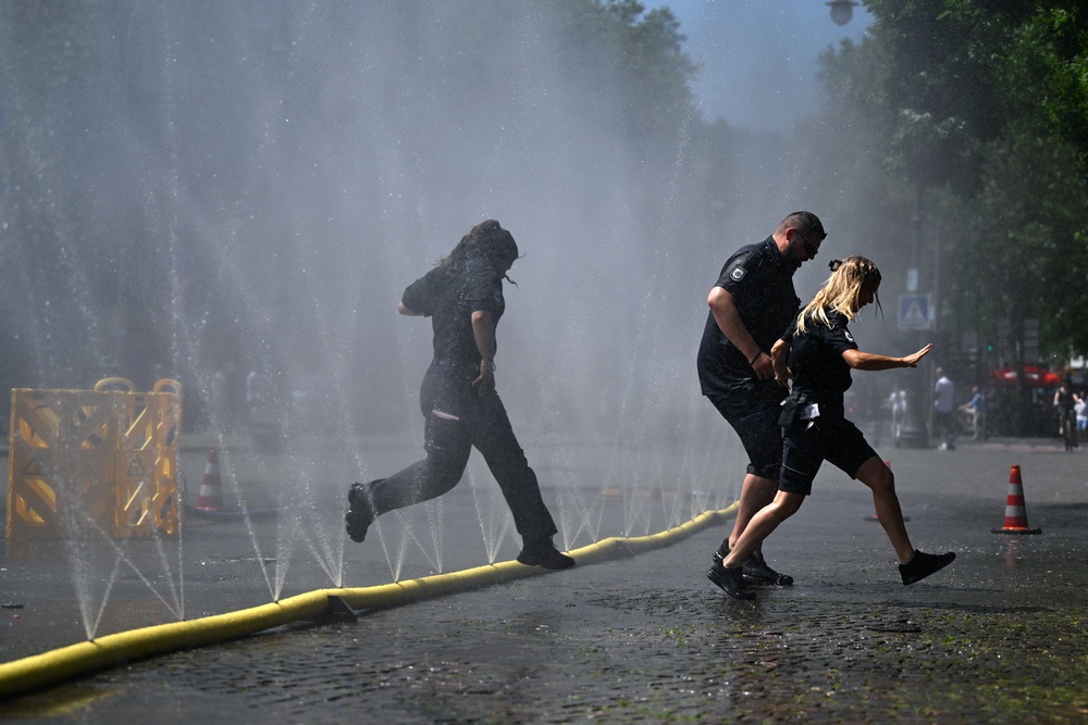 Employees of the public order office run over water hoses spilling water to provide relief from the summer heat as part of Cologne's climate adaptation measures (AFP/Getty)