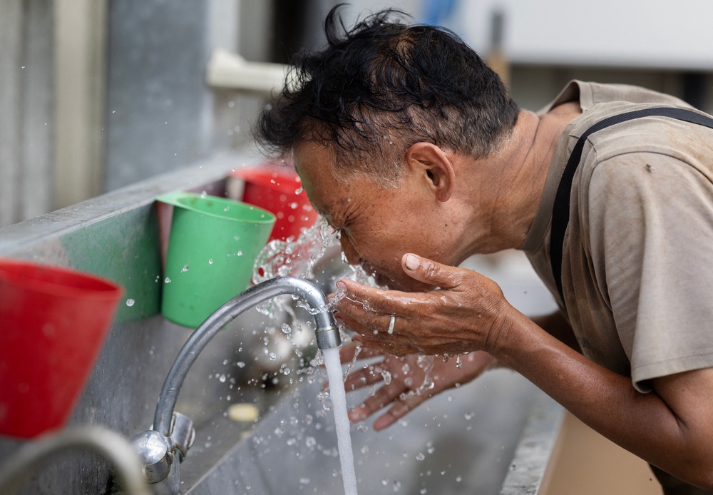 An employee puts water on his face as he works in a greenhouse of tomatoes in Taule, western Franc (AFP/Getty)