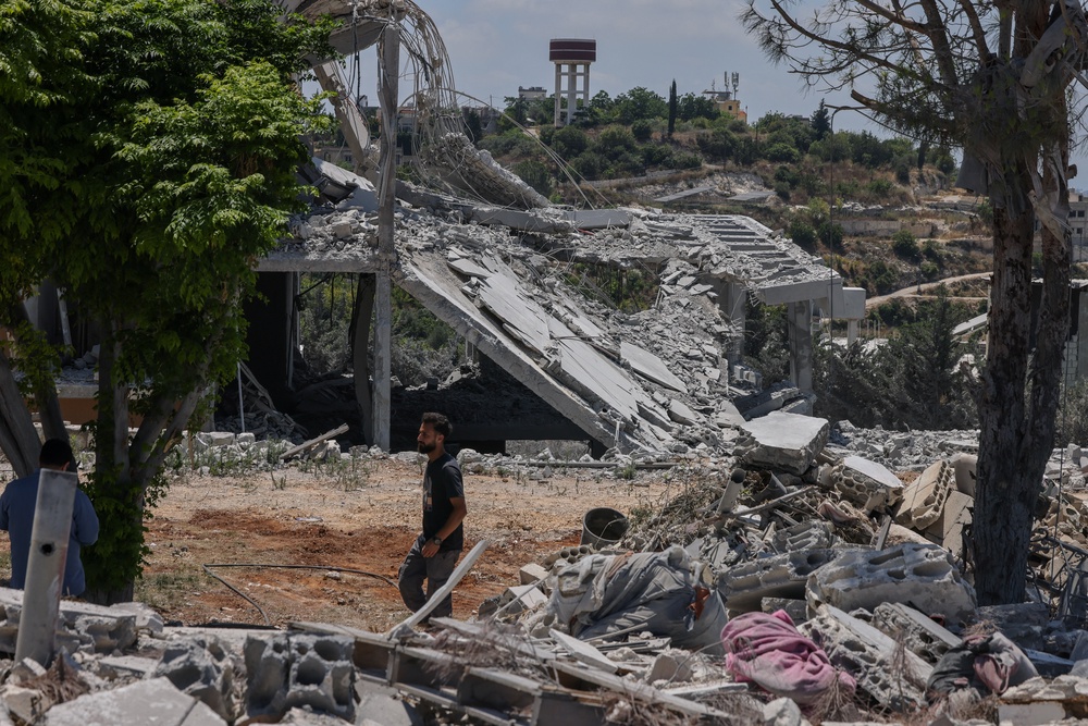 Hadi Hussein, a municipal worker who said he did not leave the village during the war, walks by houses destroyed in an Israeli airstrike in Tyre, on 25 June (Reuters)