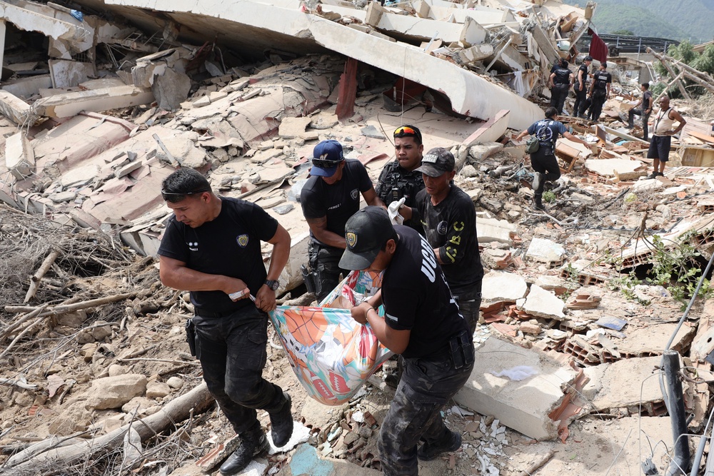Police members tend a victim amid debris of demolished buildings as rescue efforts continue in La Guaira (Getty Images)