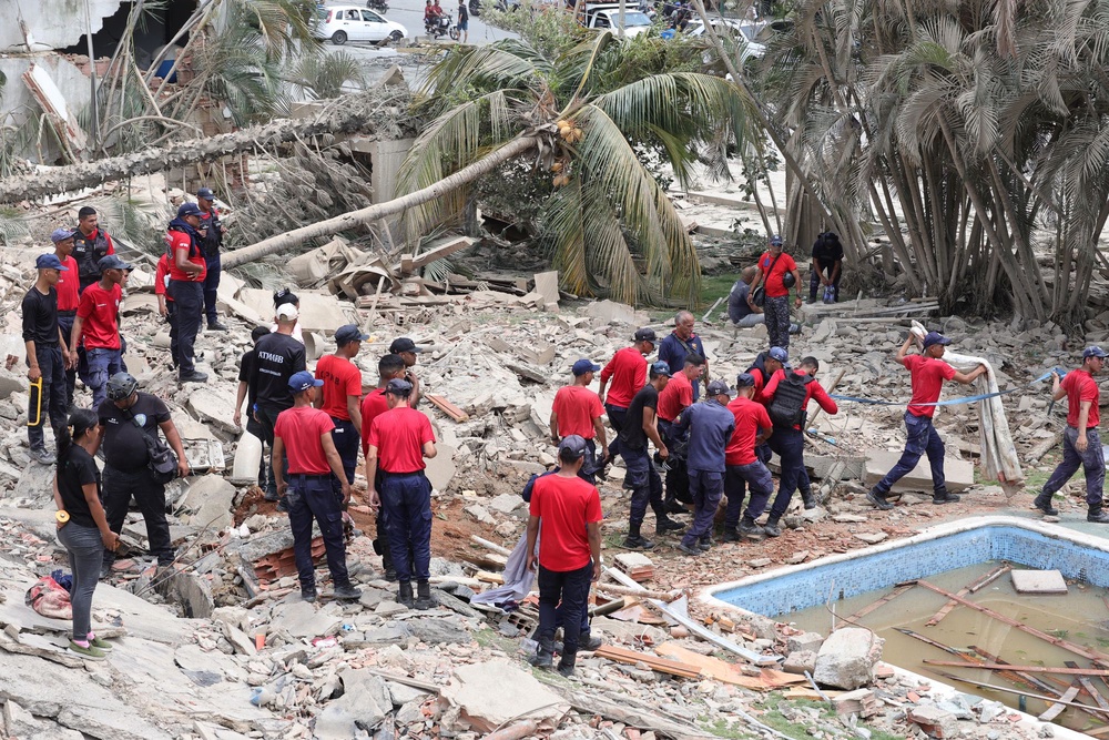 Rescue workers and police members tend a victim amid debris of demolished buildings (Getty Images)