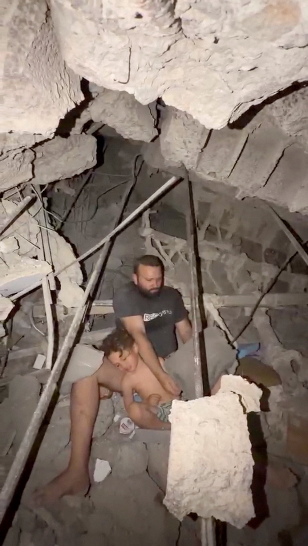 Jofram Gallipoli and his son sit under the rubble of their La Guaira building on Thursday (Reuters)