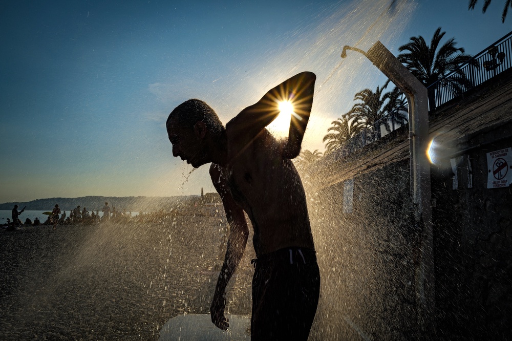 A man takes a shower on the beach along the 