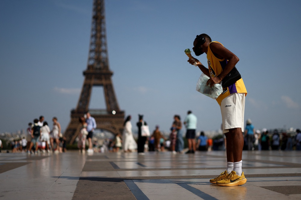 A person eats ice cream in front of the Eiffel Tower during a heatwave in Paris, France (Reuters)