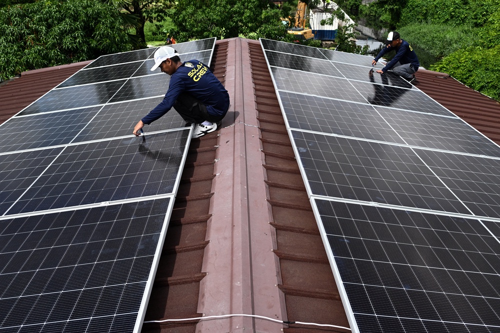 Workers install solar panels on the roof of a house in Kawit, Philippines (Reuters)