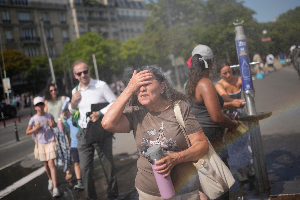FILE - Tourists enjoy cooling off at a public water fountain In Paris, on June 26, 2026. (AP Photo/Christophe Ena, File) (Copyright 2026 The Associated Press. All rights reserved.)