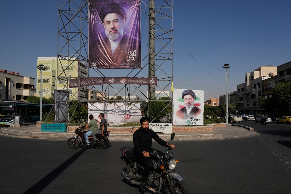 Motorbikes drive past banners showing portraits of the Iranian Supreme Leader Ayatollah Mojtaba Khamenei in downtown Tehran, Iran (AP)