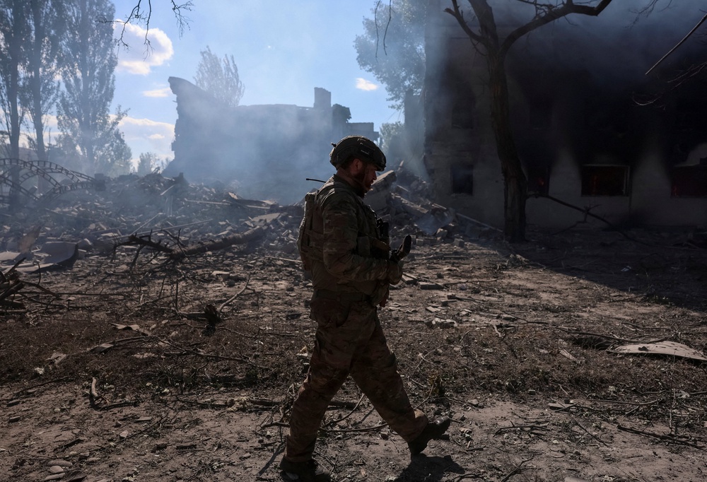 A serviceman of the 15th 'Kara-Dag' Brigade of the Operational Assignment of the National Guard of Ukraine walks near destroyed apartment buildings during his combat mission in Dobropillia (Reuters)