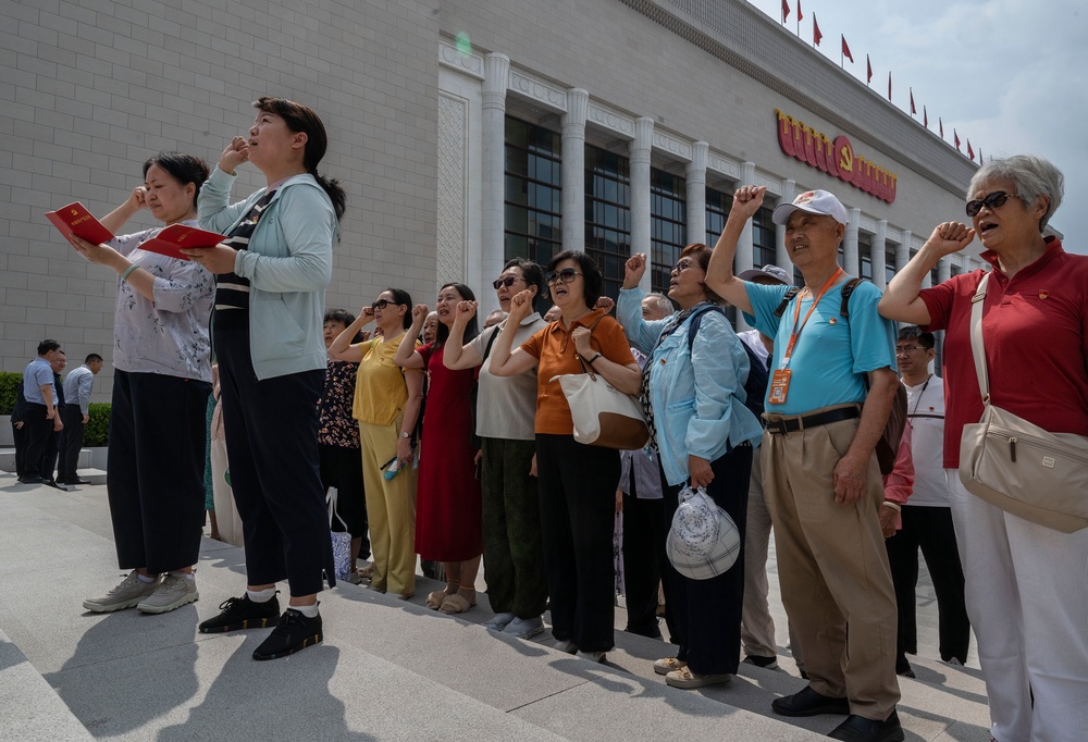 People say an oath of loyalty in front of a flag of the Communist Party of China on the 105th anniversary of its founding in Beijing on 1 July 2026 (Getty)