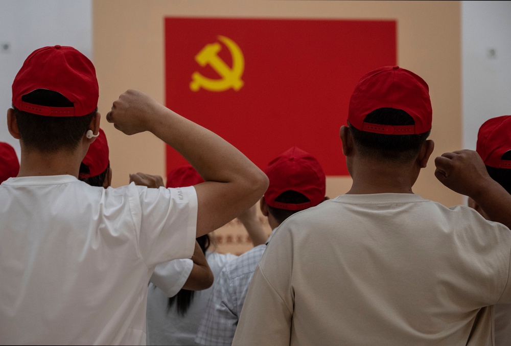 People say an oath of loyalty in front of a flag of the Communist Party of China (Getty)