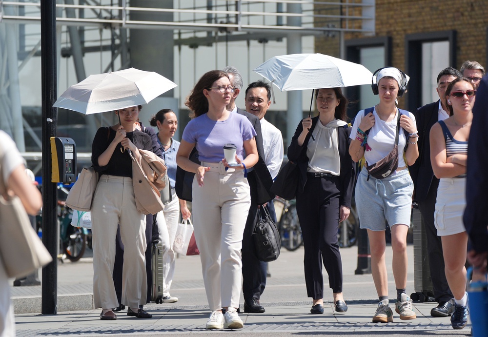 People use umbrellas for shade outside Blackfriars station in London on June 25, during the recent heatwave (Yui Mok/PA) (PA Wire)