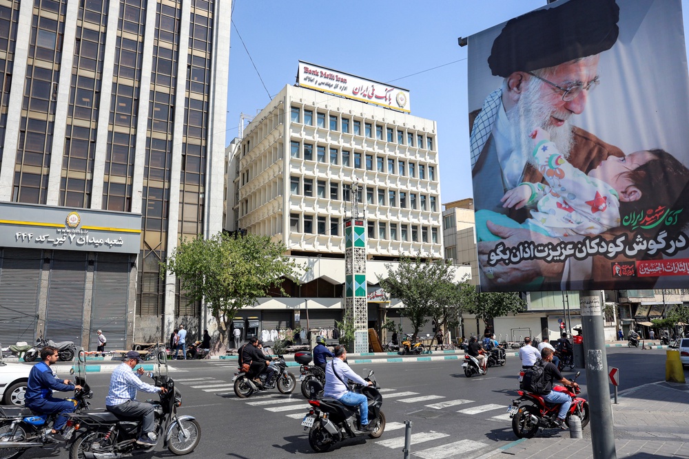 Motorists ride motorcycles along a road past a mourning billboard depicting Iran's slain supreme leader Ali Khamenei, who was killed in a strike on the first day of the US-Israeli wa (AFP/Getty)