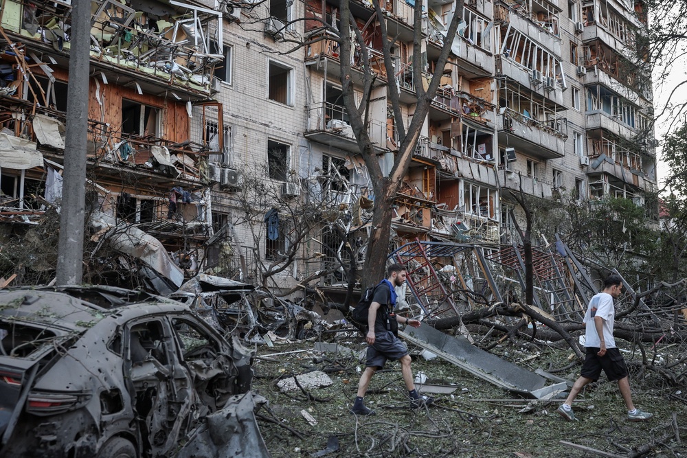 Residents pass through debris at a site of a Russian missile and drone strikes (Reuters)