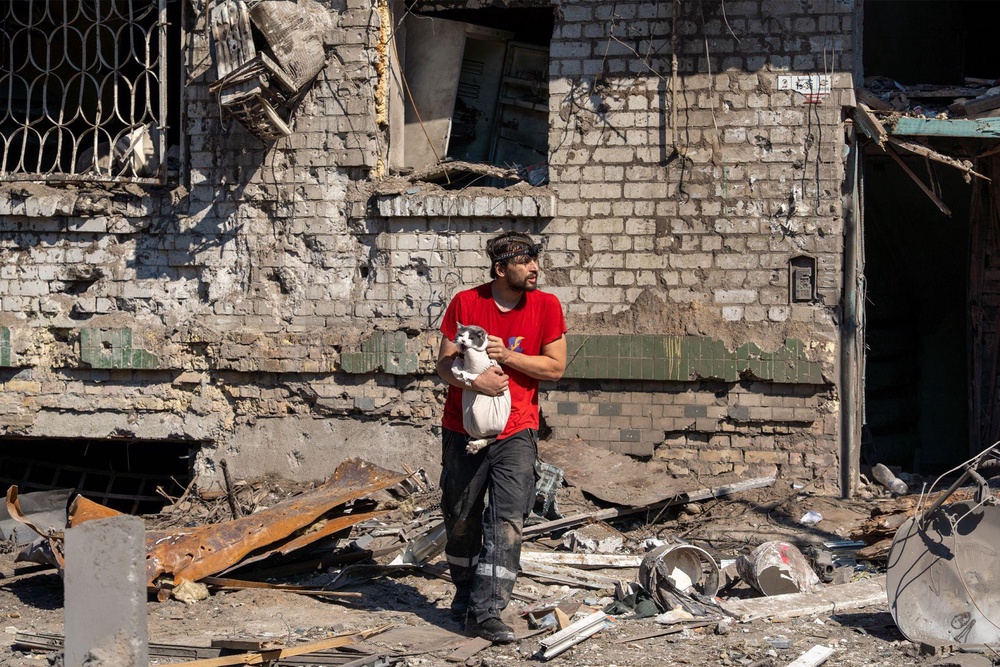 An animal rescuer rushes a cat out of a destroyed apartment block in Darnytsia, Kyiv (Tom Watling)