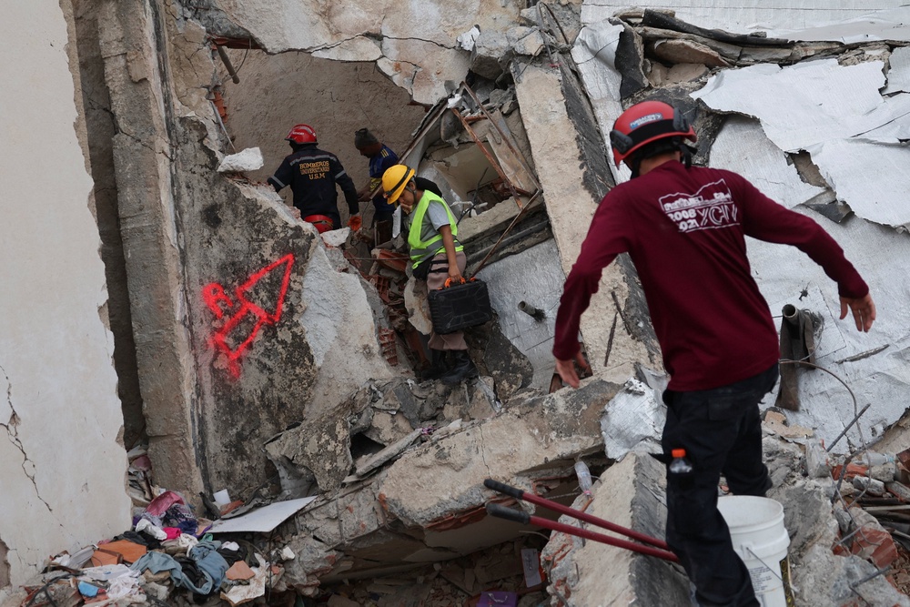 Rescuers work at the site of a collapsed building, in the aftermath of earthquakes, in La Guaira (Reuters)