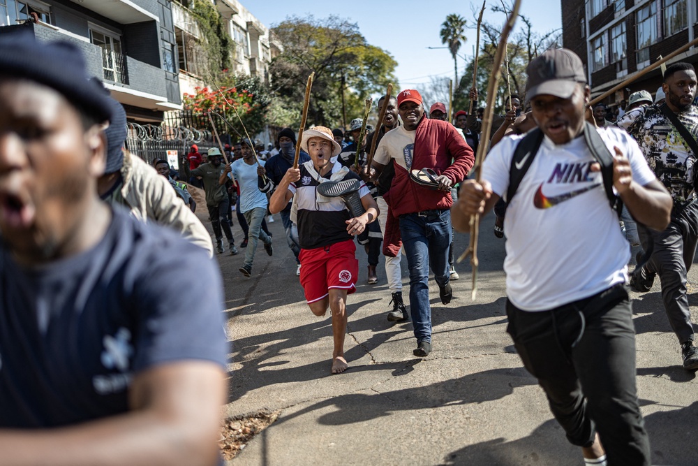 Protesters run after people they believe to be undocumented foreign nationals during a protest in Johannesburg (AFP/Getty)