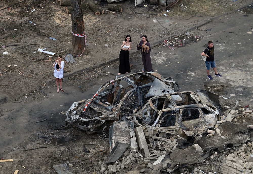 People examine burnt cars parked outside a residential building damaged following a Russian air attack on Kyiv (AFP via Getty Images)