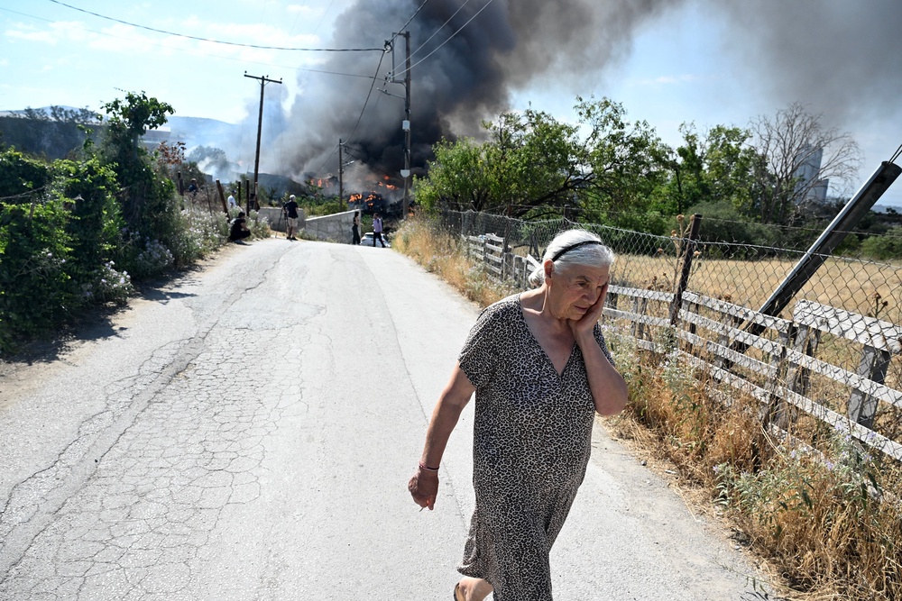 A woman reacts during a wildfire on the outskirts of the northern city of Thessaloniki, Greece (PA)