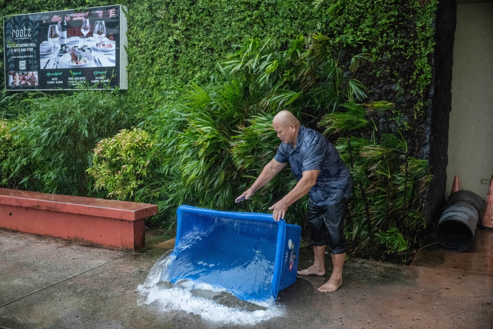 A hotel staff member removes water that leaked into a building during heavy rain brought by Super Typhoon Bavi in Guam (AFP/Getty)