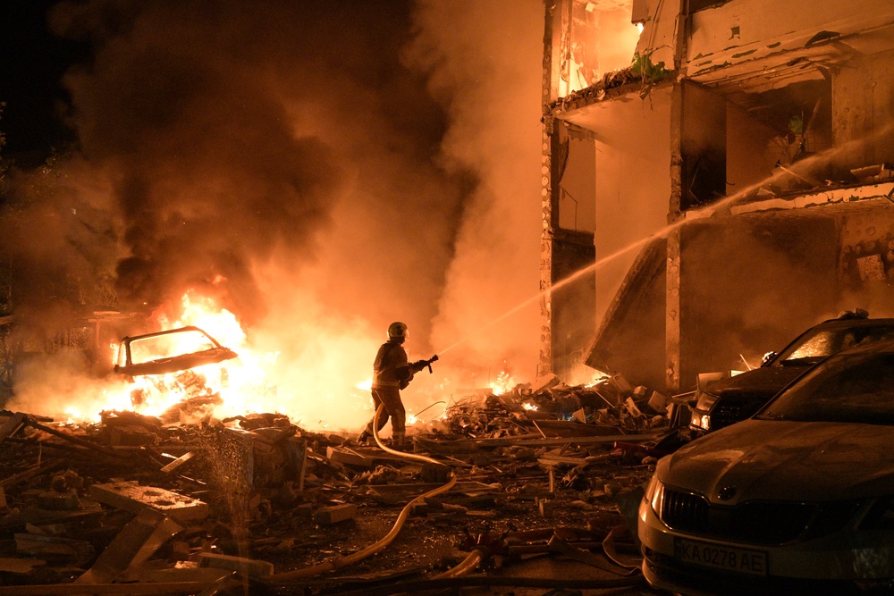 Emergency services personnel work to extinguish a fire following Russian missile attacks in Kyiv (AP)