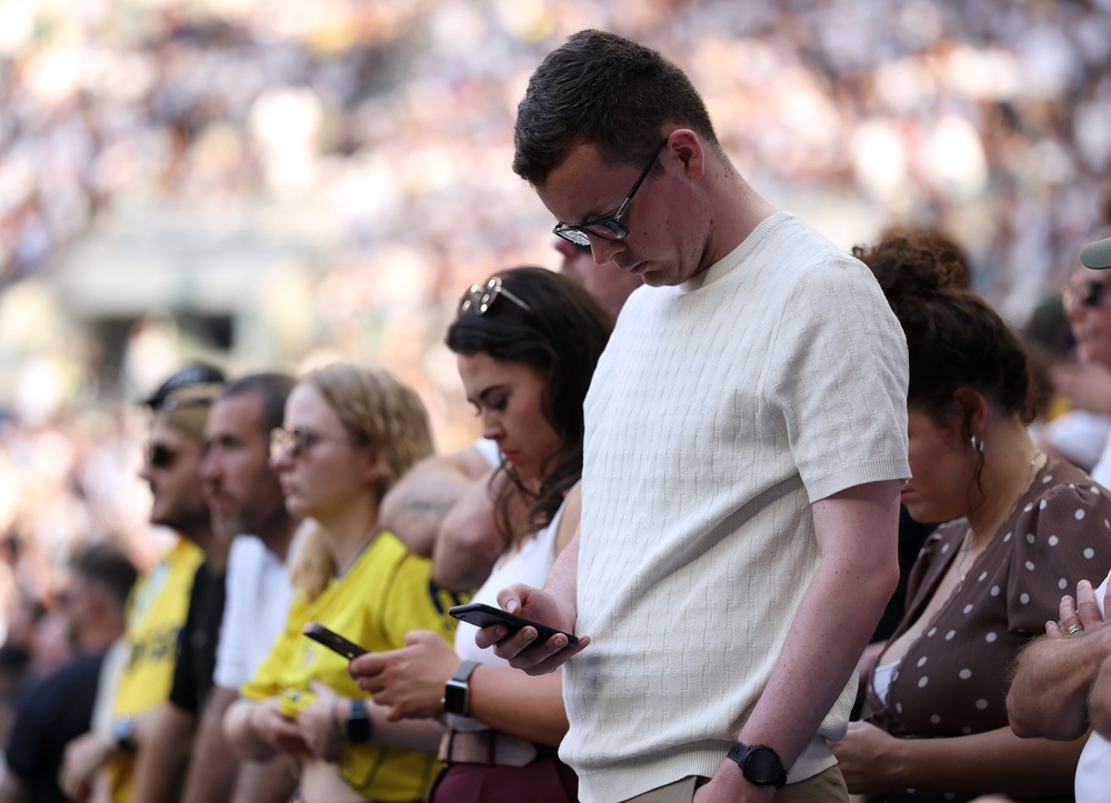 A soccer fan looks at his phone during a game last May in London, England. Tech neck can occur when looking at a smartphone, computer or other device (Getty)