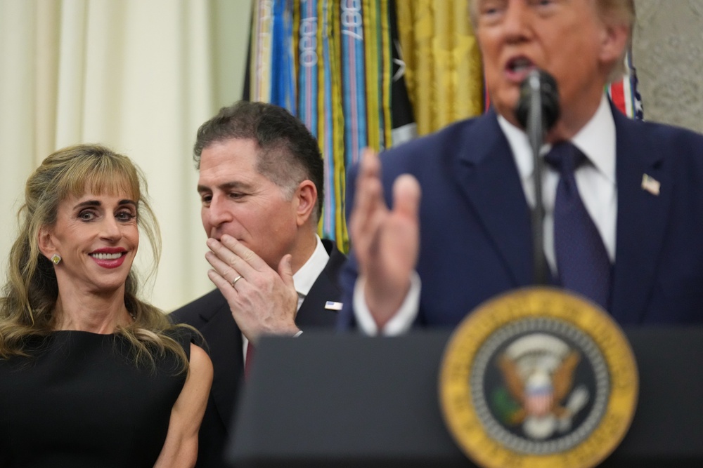Michael Dell whispers to his wife, Susan, as President Donald Trump speaks after ringing the opening bell for the New York Stock Exchange and the Nasdaq in the Oval Office. (AP)