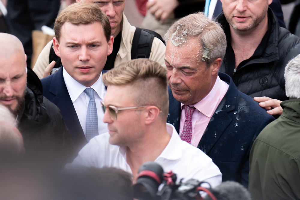 Farage with George Cottrell (left) after the former had a milkshake thrown over him in 2024 (PA)