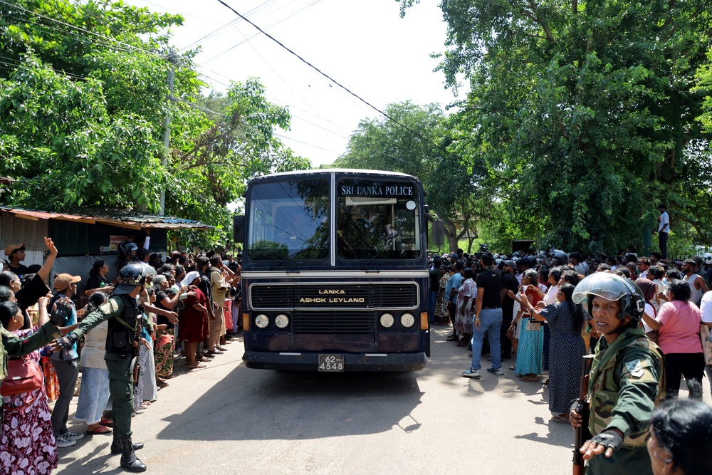 Members of security forces make way for a bus carrying prisoners to be transferred to another prison following clashes between two groups of inmates at Negombo Prison (Reuters)