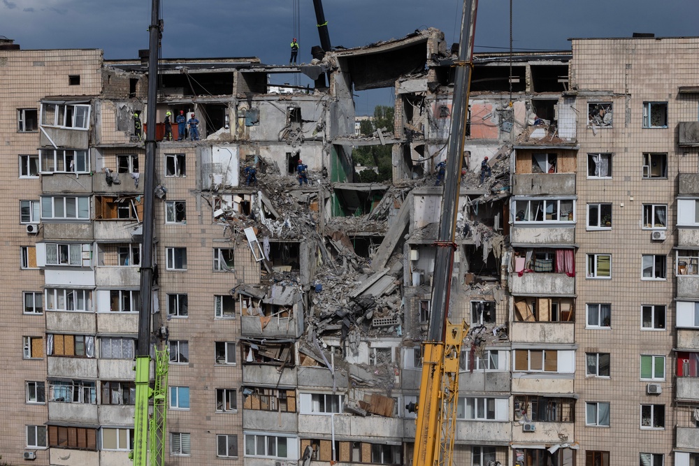 Emergency workers and machinery clear debris from the scene of an attack as Russian missiles and drones struck Kyiv overnight (Getty)
