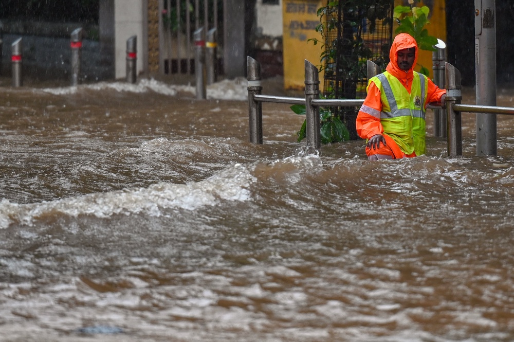 A civic authority worker stands on a flooded street during heavy rain showers in Mumbai (AFP/Getty)