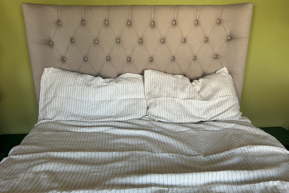 The fine pinstripes give it a bit of uniformity but you can still ditch the iron and enjoy the bedding in its lovely crumpled state (Ali Howard/The Independent)
