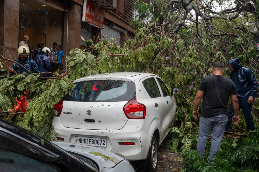 Municipal workers clear a road blocked by uprooted trees following strong winds and heavy rainfall in Mumbai (AFP/Getty)