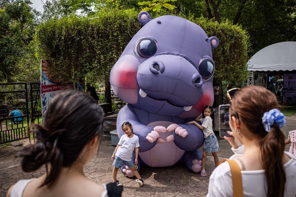 Children pose for pictures with a giant Moo Deng during a celebration of her first birthday at the Khao Kheow Open Zoo (Getty)