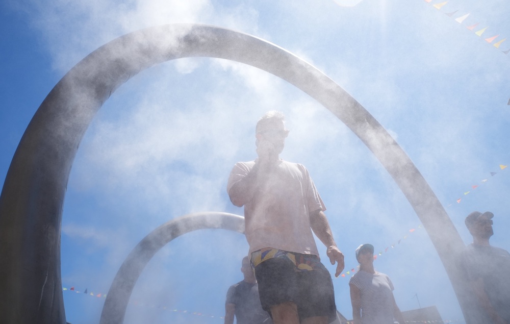 People walk through a water feature spraying a fine mist to cool off in Dover, Kent (PA)