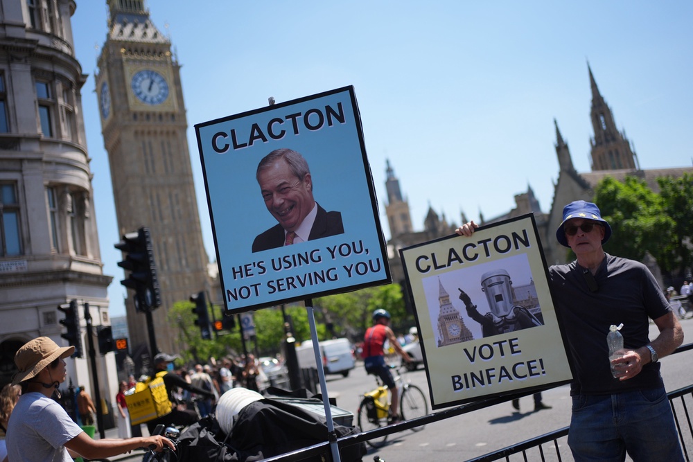 A man holds an anti-Nigel Farage placard outside the Houses of Parliament (Yui Mok/PA) (PA Wire)