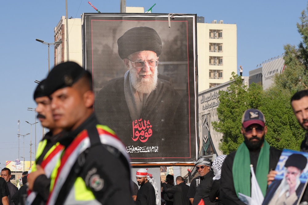 Security forces stand guard in front of a portrait of Iran's slain supreme leader Ali Khamenei as mourners gather for a funeral procession in Najaf on July 8, 2026 (AFP/Getty)