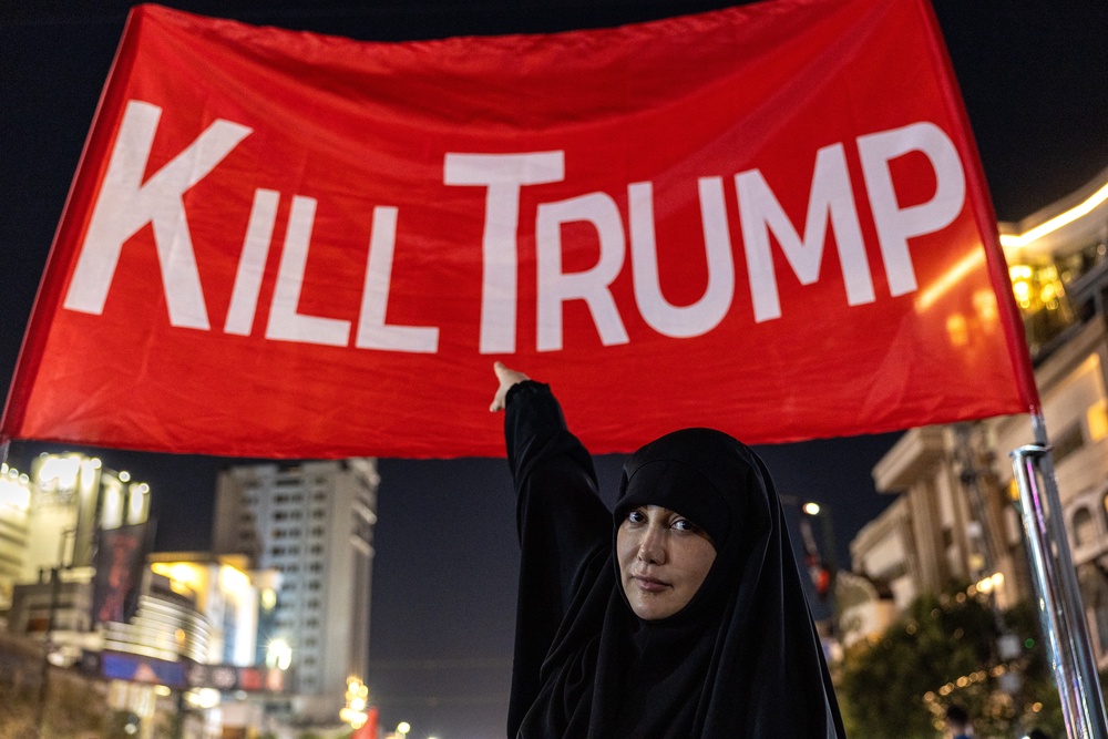 Mourners pose for photos under a banner set up in a main thoroughfare near the Imam Reza Shrine (Getty)