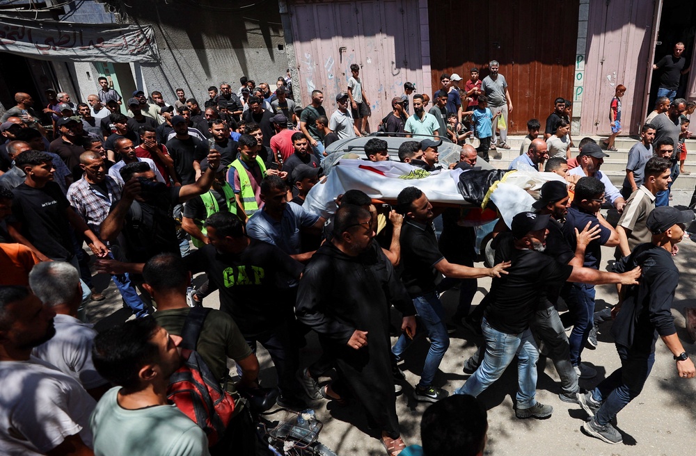 Mourners carry the body of Palestinian man Mohammad al-Waheidi, who worked for the Egyptian Relief Committee and was killed in an Israeli strike on Tuesday, during his funeral, in Gaza City, July 8 (Reuters)