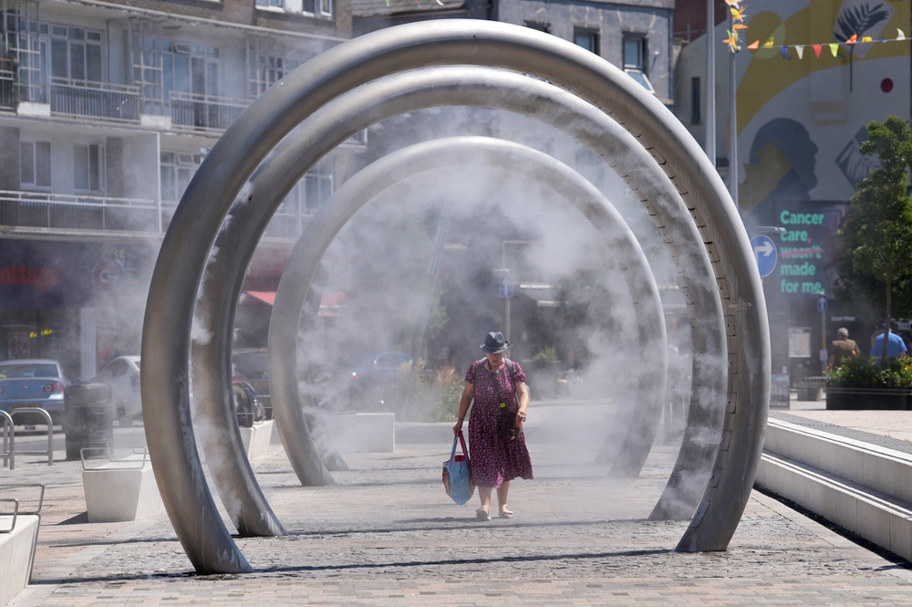 A lady walks through a water feature spraying a fine mist to cool off in Dover, Kent (Gareth Fuller/PA) (PA Wire)
